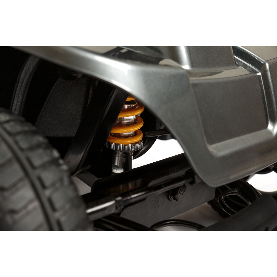Close-up of the Pride Mobility Revo® 2.0 4-Wheel Scooter’s suspension, featuring a yellow coil spring, wheel, and fender, showcasing its sturdy build and detailed mechanical design.