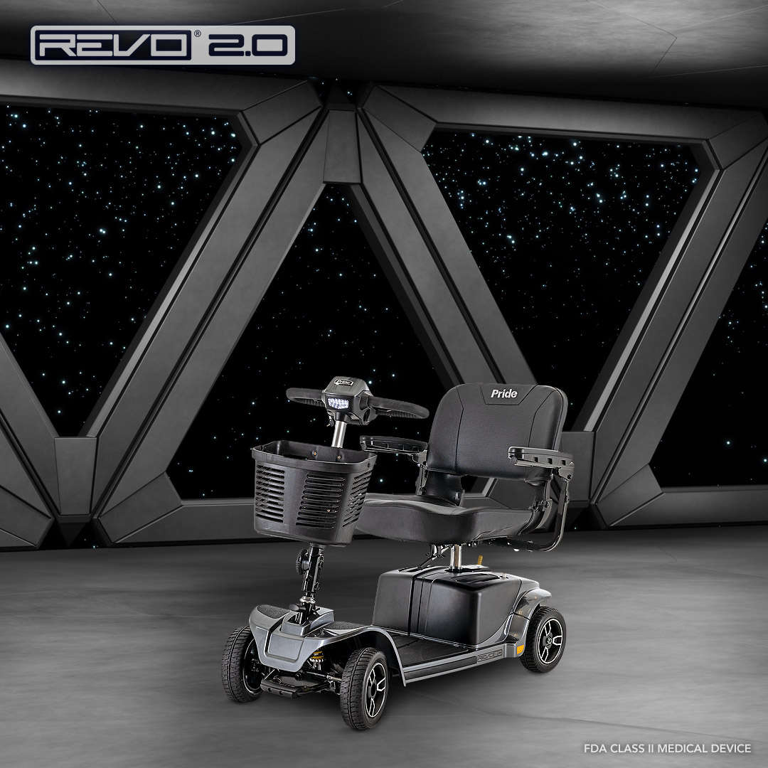 A black Pride Mobility Revo® 2.0 4-Wheel Scooter is displayed in a futuristic room with large geometric windows overlooking a starry night. The scooter includes a front basket, armrests, and is ready for use.