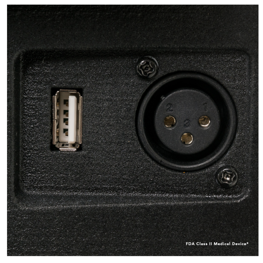 Close-up of the black control panel on a Pride Mobility Victory® 10.2 Bariatric 3-Wheel Scooter, showing a USB port on the left and a three-pin circular XLR connector on the right, with textured finish and visible small screws.