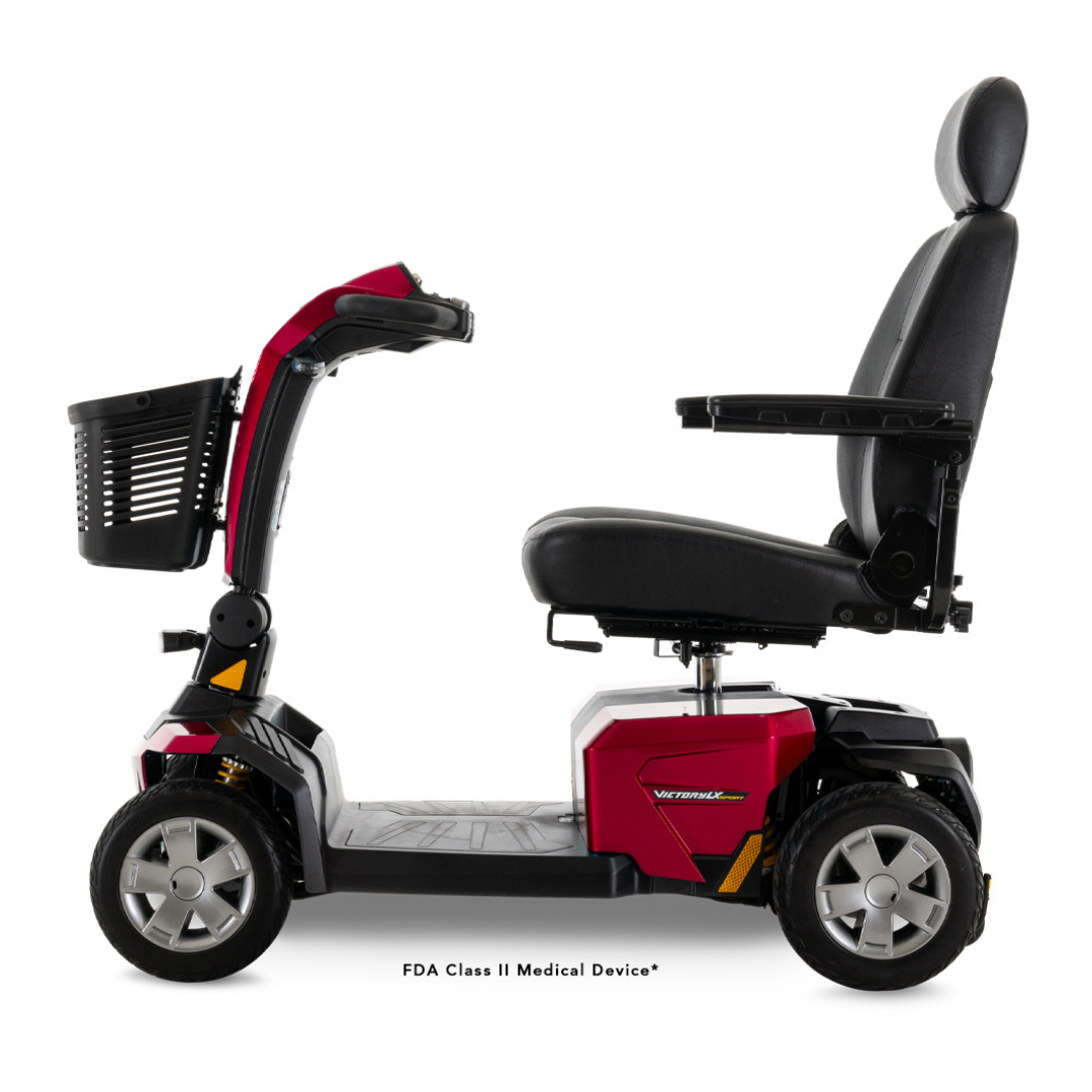A Pride Mobility Victory LX Sport Scooter in red and black, featuring Comfort-Trac Suspension, a front basket, padded seat with armrests, and four wheels, is shown in side profile against a white background.