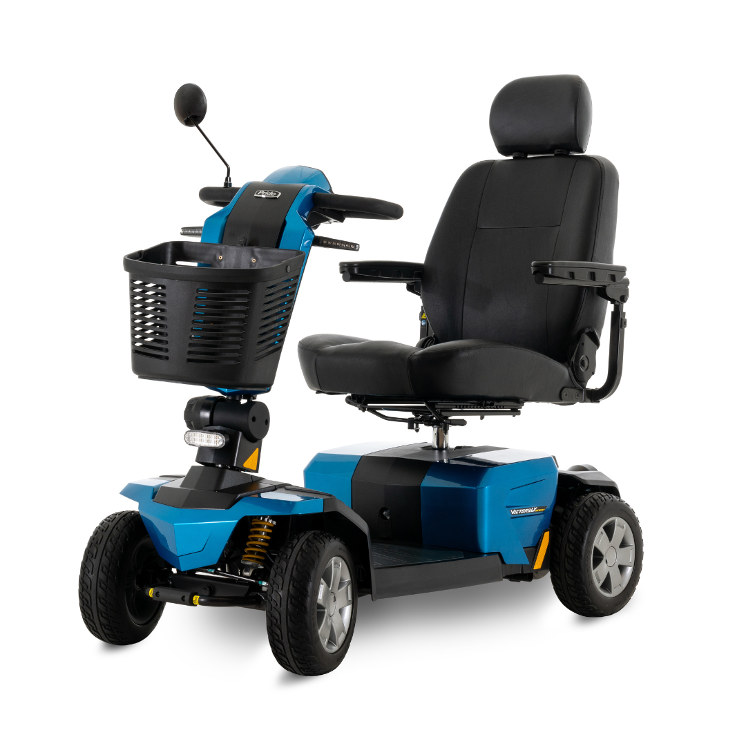 The Pride Mobility Victory LX Sport Scooter is a blue and black, four-wheel model with Comfort-Trac Suspension, cushioned seat with armrests and headrest, front basket, handlebars, and a small headlight.