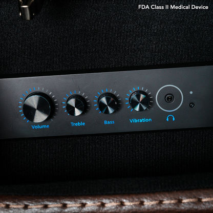Close-up of the black control panel on the Pride VivaLift! Premier Recliner With Assisted Lift, Audio & Massage. Blue-lit dials labeled Volume, Treble, Bass, Vibration, and a headphone jack. FDA Class II Medical Device text is shown.