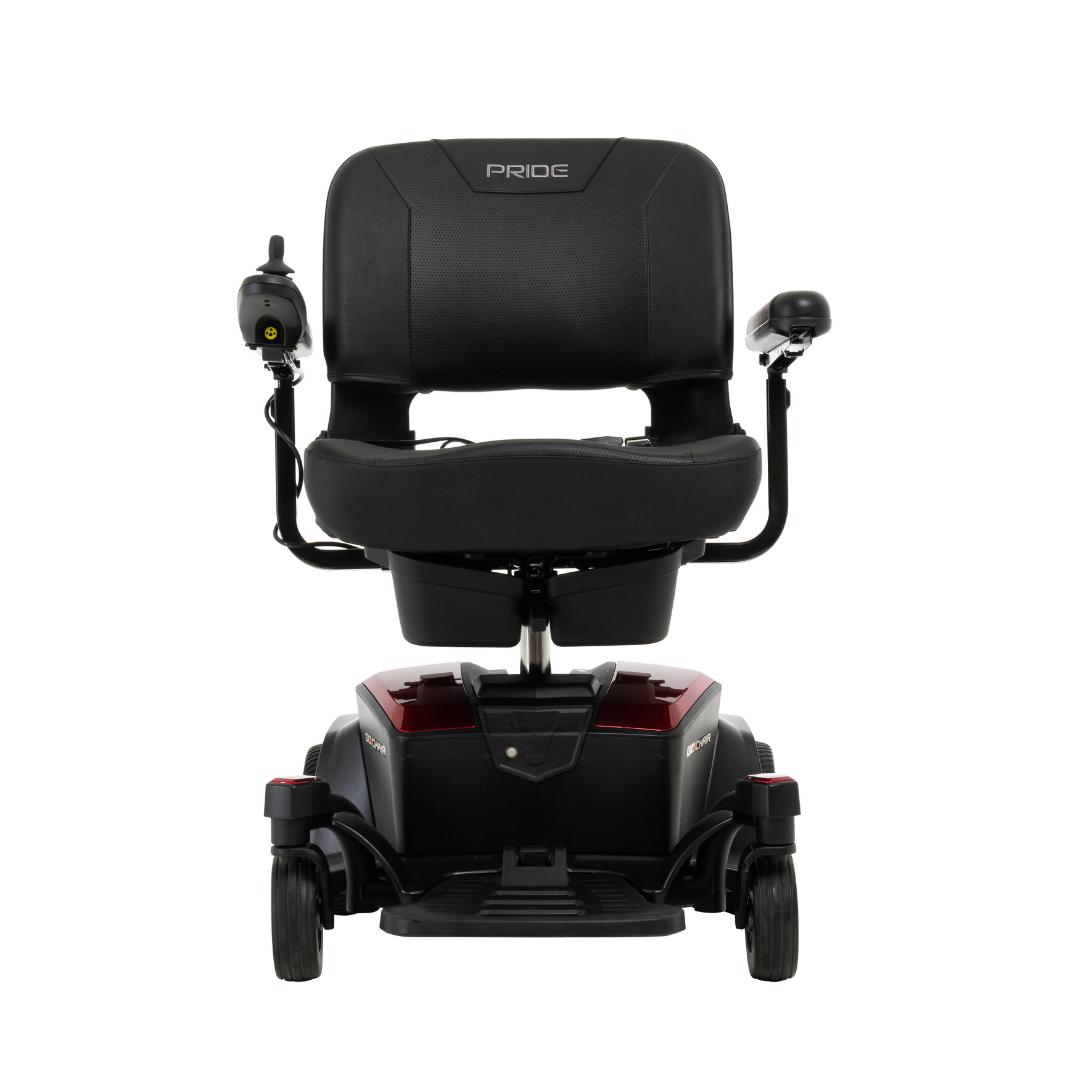 Front view of the Pride Mobility Go Chair® Portable Powerchair in black and red, featuring a padded seat, armrests, left-side joystick control, small wheels, compact turning radius, and Pride branding on the backrest.