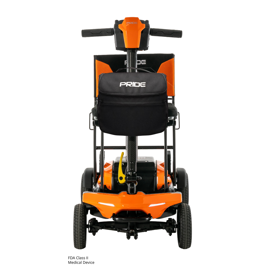The Pride Mobility Go Go® Super Portable Mobility Scooter is a compact orange scooter with large wheels, PRIDE branding on the seat and backrest, and a rear black storage pouch—ideal for travel with its airline-approved lithium battery.