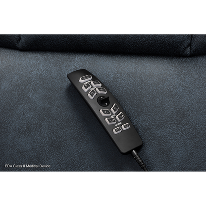 A black remote with gray buttons and a cord rests on the dark blue upholstery of a Pride Mobility VivaLift! Radiance Recliner with Lift Assist & Heat. FDA Class II Medical Device appears in the lower left corner.