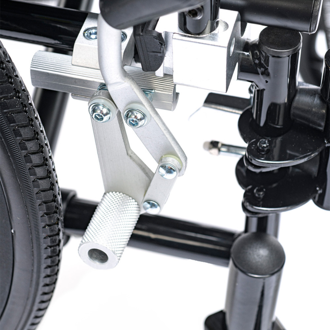Close-up of the Proactive Chariot IV XTC-RC Pediatric Folding Reclining Wheelchair’s silver brake mechanism, mounted by a black wheel on its carbon steel frame, highlighting detailed bolts and a textured grip handle.