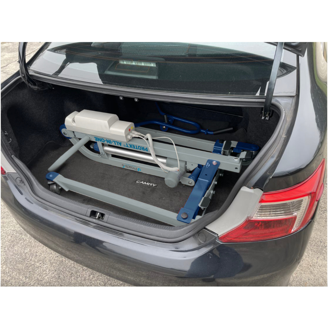 The Proactive Protekt® All-In-One Transfer Power Lift - Portable Car Lift is folded and placed in the trunk of a dark-colored sedan, showcasing its compact size and easy portability.