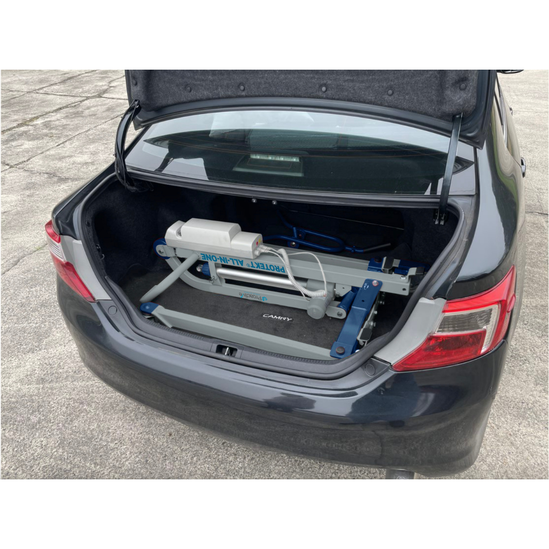 A Proactive Protekt® All-In-One Transfer Power Lift - Portable Car Lift is stored in the trunk of a black Toyota Camry on concrete, demonstrating the lift’s portability and ease of transport and storage.