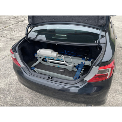 A Proactive Protekt® All-In-One Transfer Power Lift - Portable Car Lift is stored in the trunk of a black Toyota Camry on concrete, demonstrating the lift’s portability and ease of transport and storage.