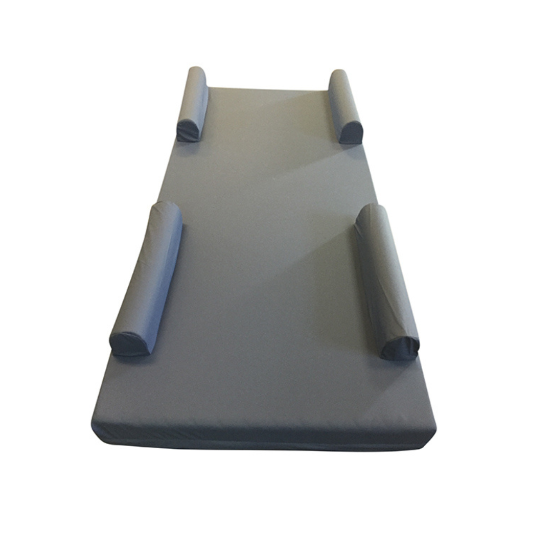 The Proactive Raised Rail Mattress Cover is a gray rectangular safety cover with four cylindrical foam rail bolsters—two at the top and two at the bottom sides—for entrapment protection, shown on a plain white background.