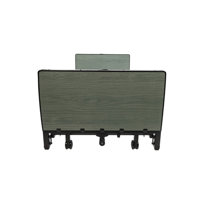 A foldable table with a green wood grain surface and black legs—displayed in a side view with wheels at the base—is an excellent complement to the Protekt Akra-FE™ Full-Electric Bariatric “Low” Bed for use in a homecare environment.
