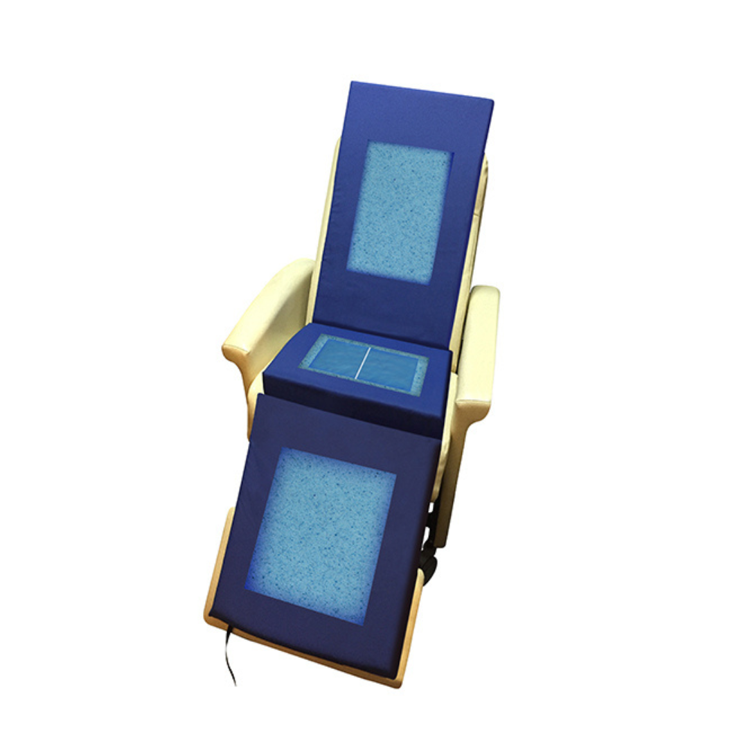 A padded blue medical recliner with cream-colored armrests, featuring rectangular blue gel pads on the backrest, seat, and leg support, is fitted with a Protekt® Geri-Chair Foam Overlay for enhanced comfort and support. The chair is viewed from above against a white background.