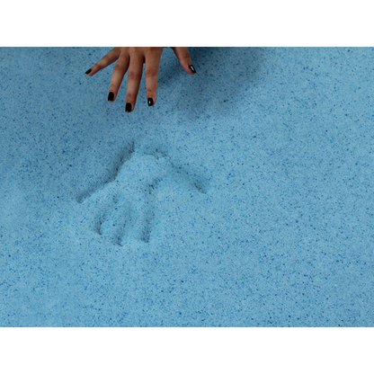 A hand with black-painted nails hovers above light blue sand, leaving a clear handprint—showcasing the soothing, pressure-relieving comfort of the Protekt® Ultra Molded Dual-Layer Portable Mobility Cushion.