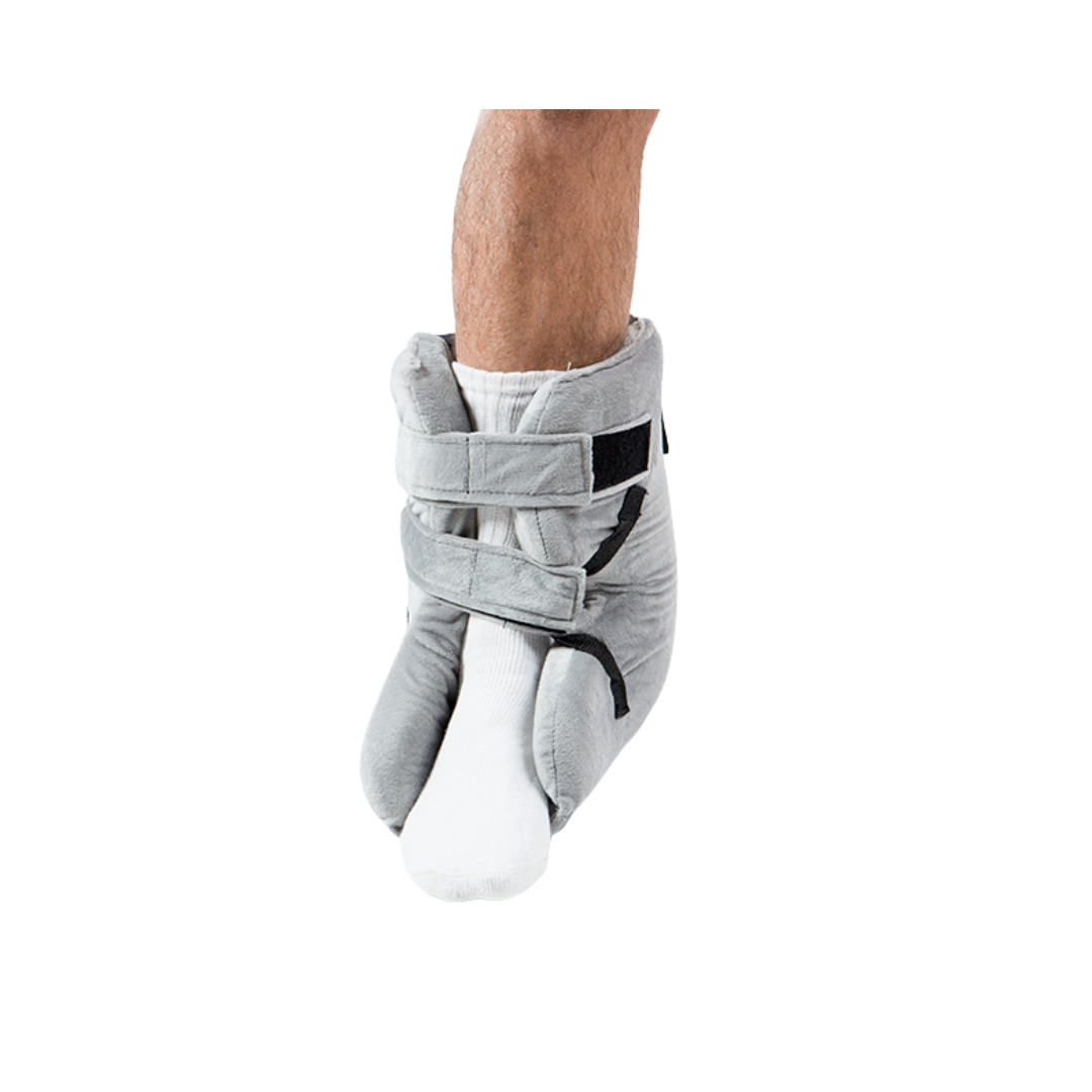 A person’s lower leg and foot in a white sock wear the Proactive Protekt® Heel Gel Elevation Boot with Hot or Cold Gel Pack, a gray padded boot with two Velcro straps for pressure sore prevention, shown against a white background.
