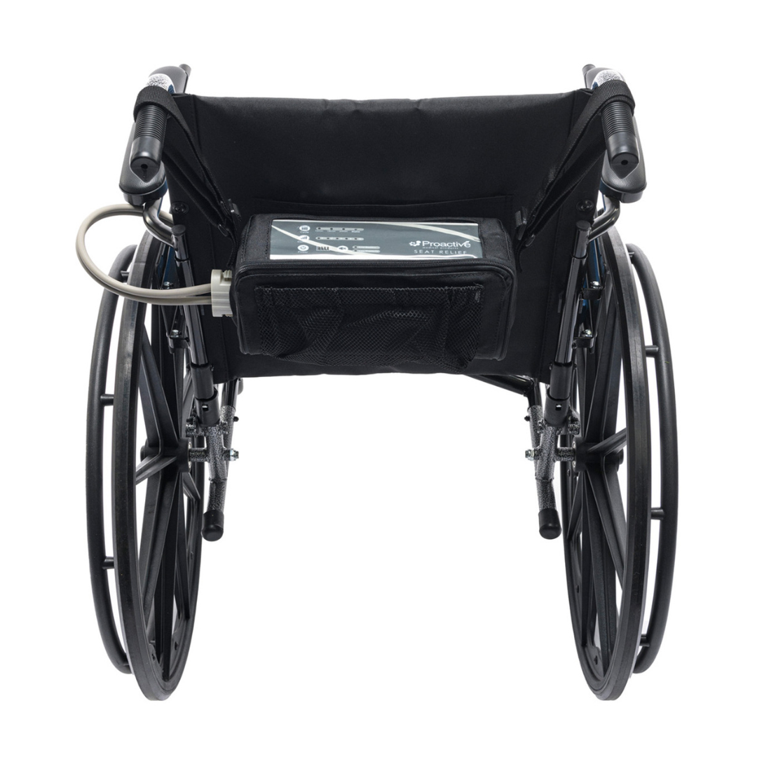 Rear view of a black manual wheelchair with large wheels, featuring the Protekt® Seat Relief Alternating Pressure Seat Cushion System by Proactive and a small transparent tube to a control panel for pressure injury prevention.