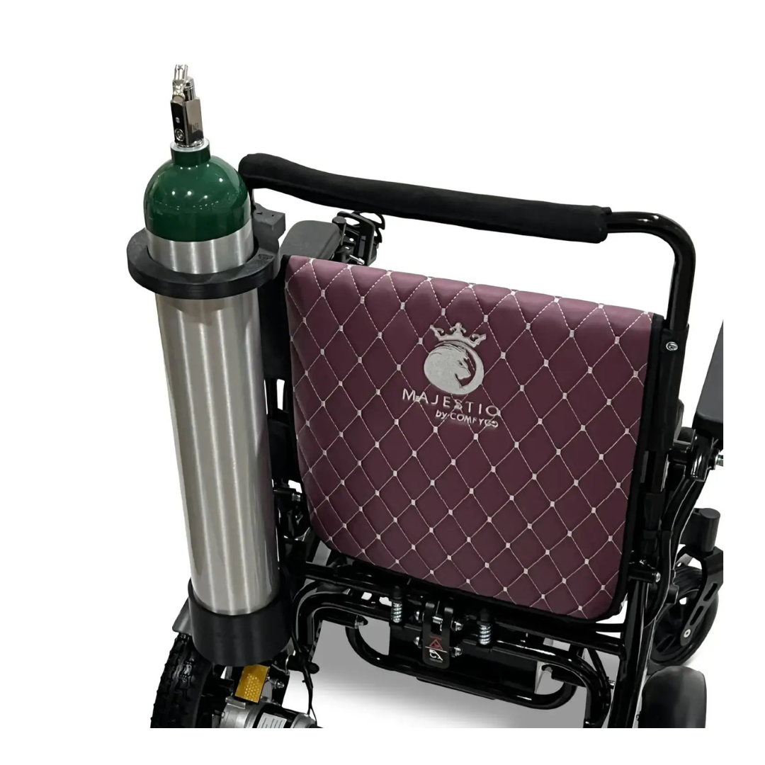 A COMFYGO powerchair with a maroon quilted backrest labeled "MAJESTIC" and a Quick Detach Oxygen E Tank Holder mounted on the side.