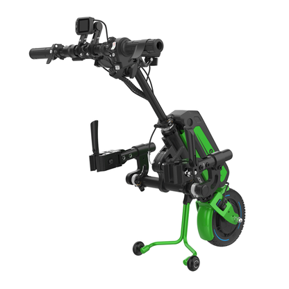 A compact green and black Rehasense ECO Travel LX Power Add-On – Lightweight Wheelchair Motor Assist, designed for manual wheelchairs with handlebars, a control panel, one front wheel, and two stabilizer wheels.