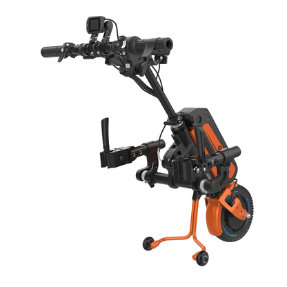 A black and orange Rehasense ECO Travel LX Power Add-On – Lightweight Wheelchair Motor Assist, with handlebars, a front wheel, digital display, and support legs for stability, for use with manual wheelchairs.