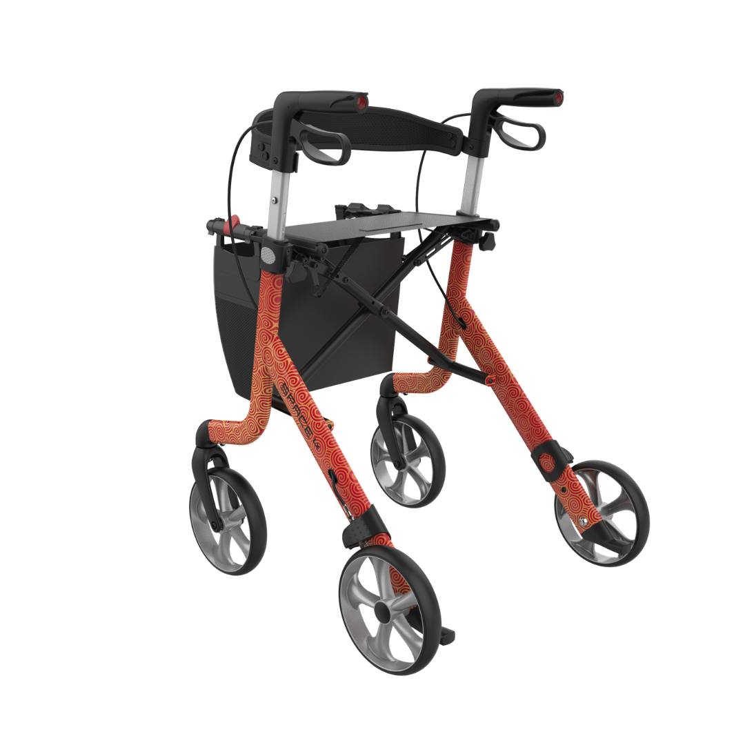 The Rehasense Space LX Art Deco Ultralight Rollator features orange patterned aluminium legs, ergonomic handles, hand brakes, and a black storage bag. It is shown against a white background.