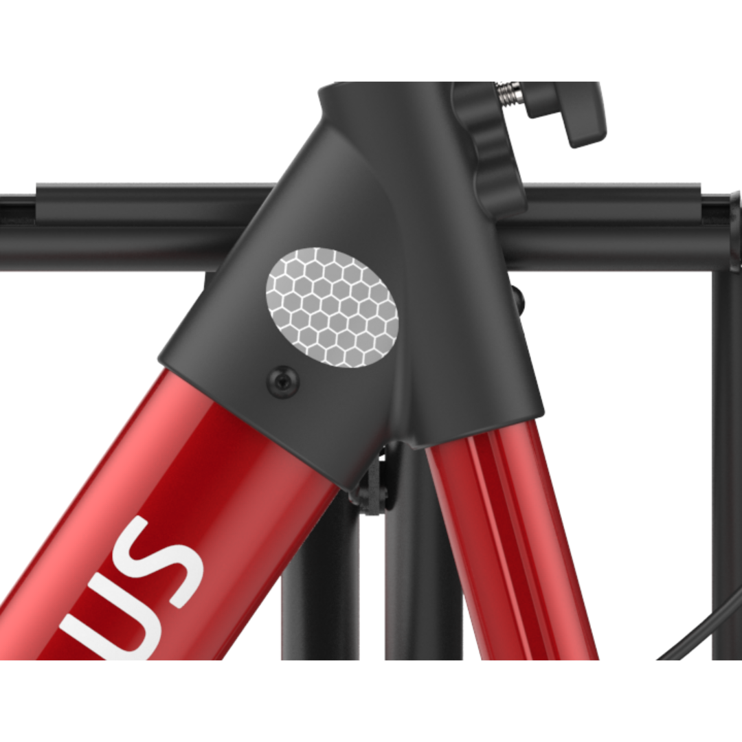 Close-up of a red Rehasense Stylus Premium Indoor & Outdoor Rollator frame with a black joint and silver honeycomb-patterned reflector. A partial white 'S' is visible, with black rack bars in the background—sturdy design details highlighted.