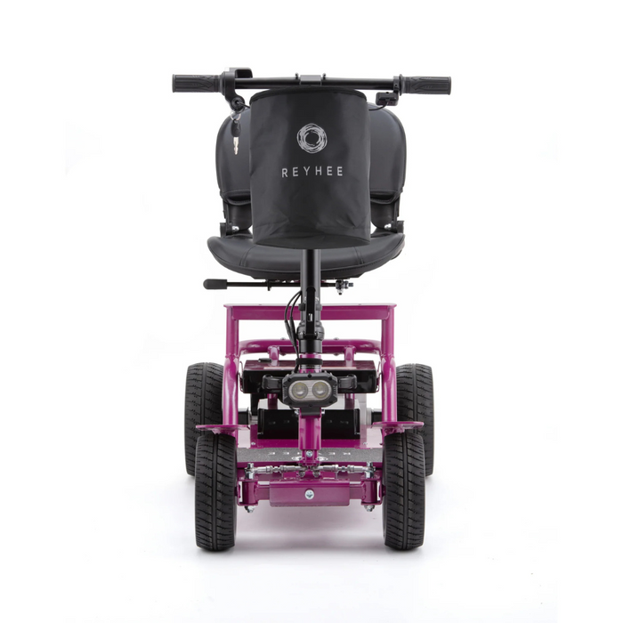 The Reyhee EXO Portable 4-Wheel Mobility Scooter, in pink, features a sturdy frame with a black seat and backrest. It flaunts textured tires, visible wiring below the seat, and showcases its brand name in the front view.