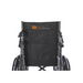 The Rhythm Deluxe Reclining Desk Arm Wheelchair by Rhythm Healthcare features a sleek black design with a back pocket and their distinctive orange and white logo on the backrest. It is equipped with a chrome frame, elevating leg rests, and easily noticeable quick-release rear wheels.