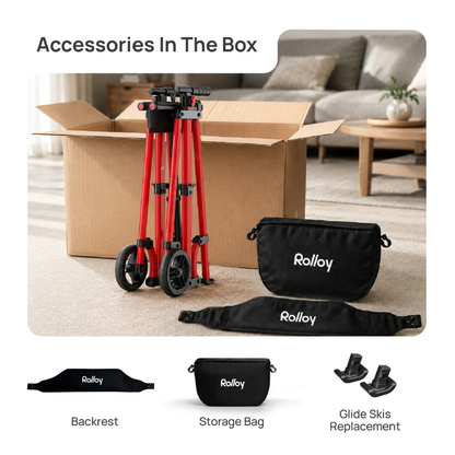 An open box holds the folded Rolloy Compact Master Bariatric 2-Wheel Walker with Seat. In front are a black backrest, storage bag, and two glide ski replacements, shown on a living room floor with sofa and table in the background.