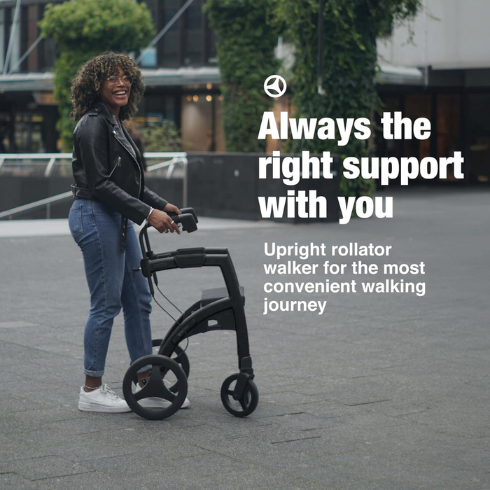 A person with curly hair and glasses, dressed in a black jacket and jeans, smiles while walking with the Rollz Motion 2-in-1 Rollator Walker and Wheelchair. Text reads: Always the right support with you. Enjoy a convenient walking journey.