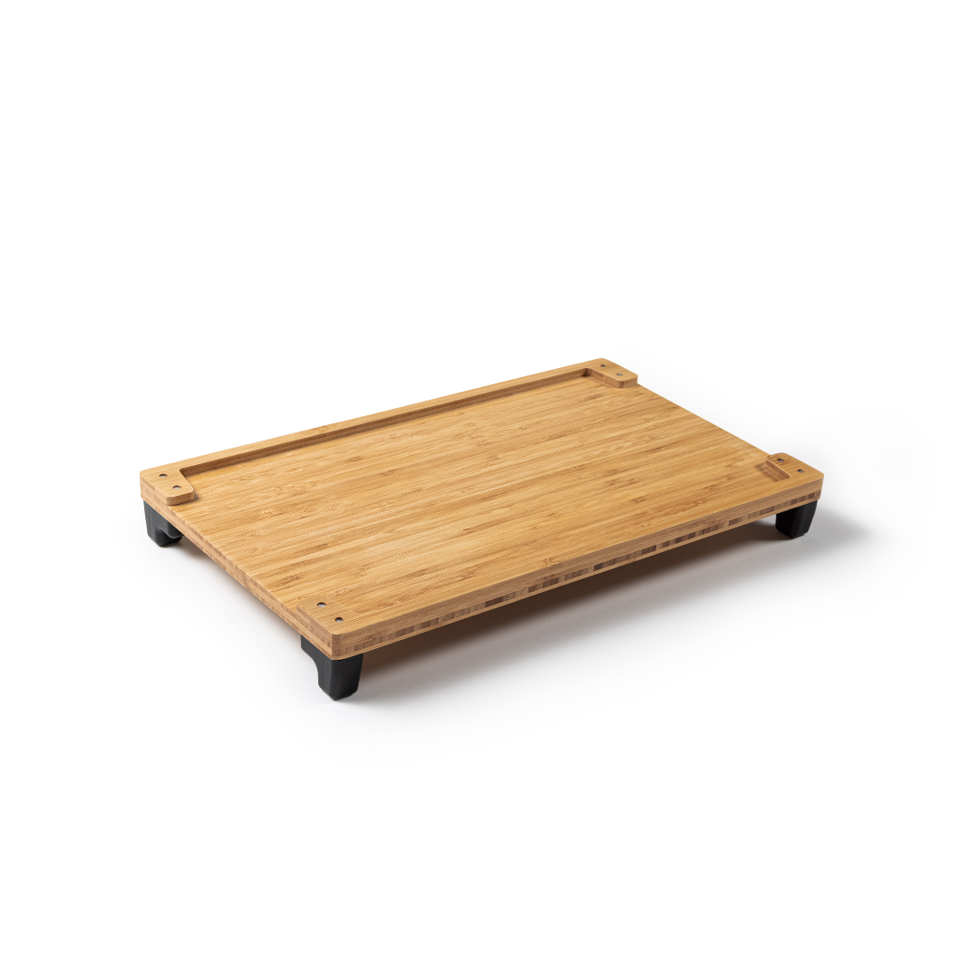 A wooden cutting board with a smooth surface and four small black feet at each corner, slightly elevating it from the surface, resembles accessories for the Rollz Motion Rollator. Its natural finish beautifully showcases the wood grain.