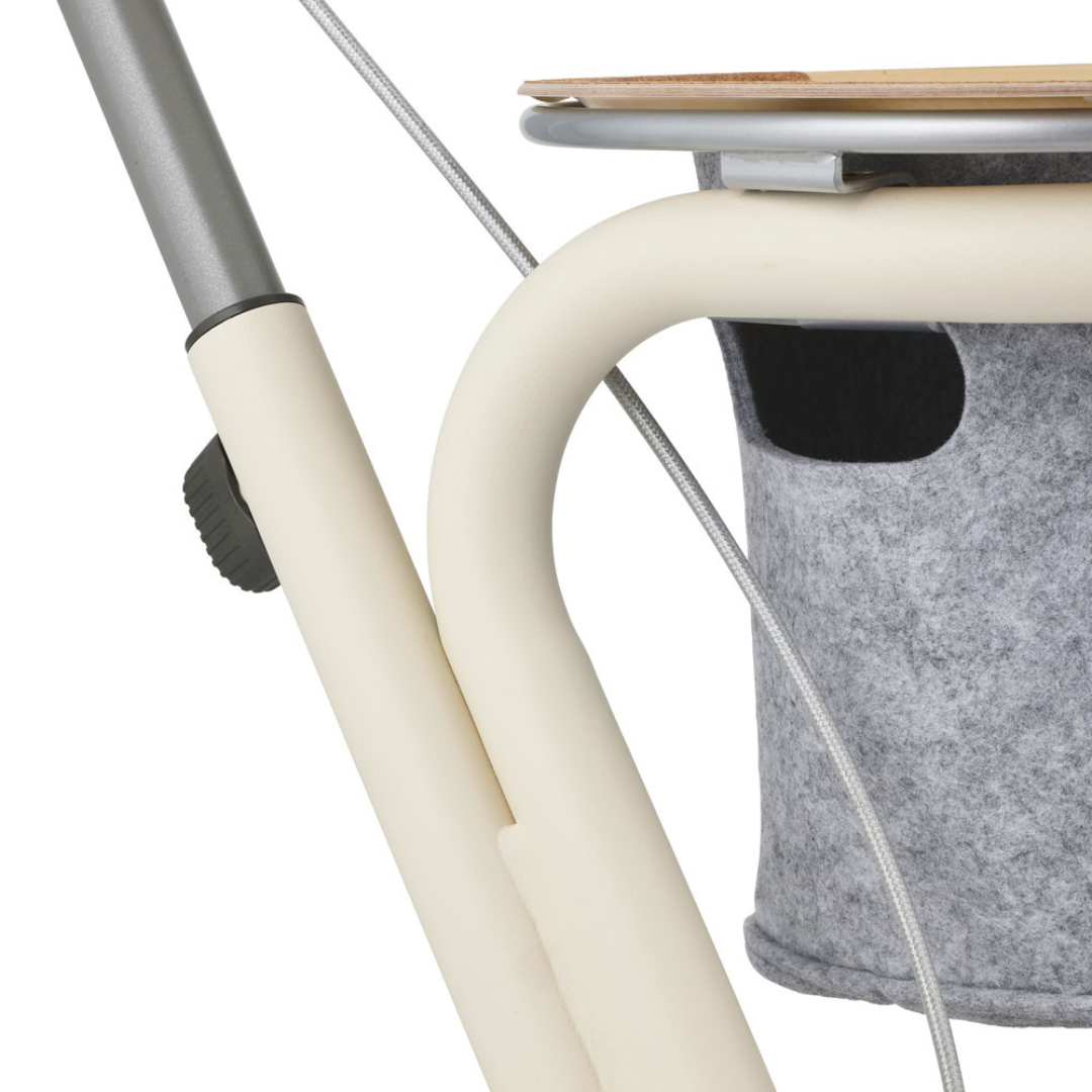Close-up of the byACRE Scandinavian Butler At-Home Rollator, showcasing its cream metal frame, adjustment knob, and gray felt storage pocket beneath the wooden seat—an elegant mobility aid for your home.