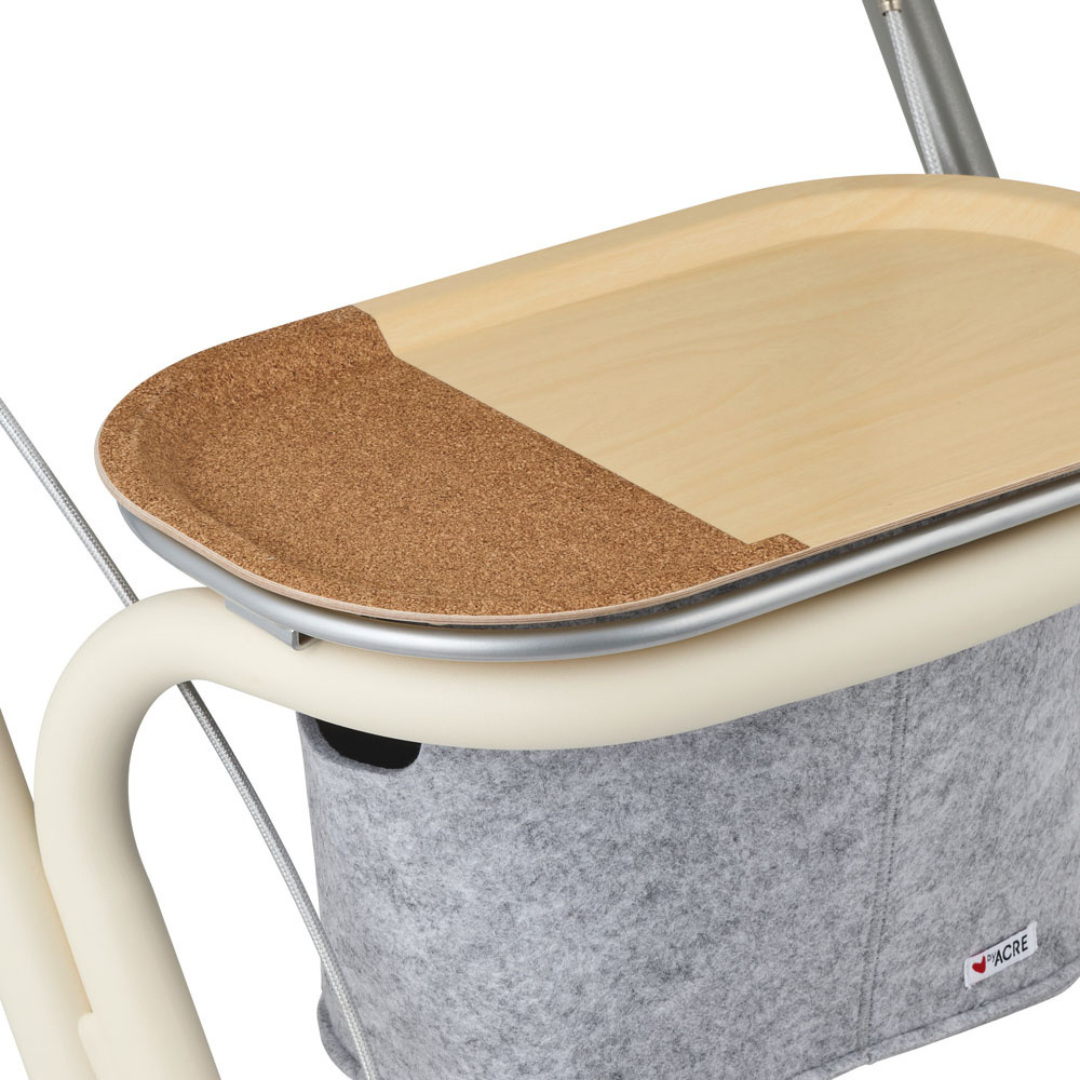 A close-up of the byACRE Scandinavian Butler At-Home Rollator shows its light wood seat with brown cork, a beige metal frame, and a gray felt storage pocket—showcasing clean Scandinavian design lines.