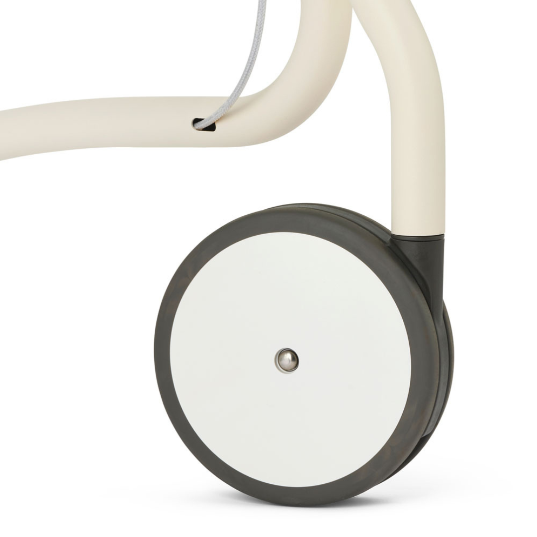 Close-up of a minimalist wheel on the byACRE Scandinavian Butler At-Home Rollator, showing a smooth white hubcap with a black rim attached to its light-colored metal frame.