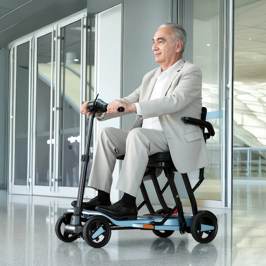 An older man in a light suit smiles as he rides the ScootNgo Voyager Lightweight Folding Scooter down a modern hallway with glass walls and a shiny floor.