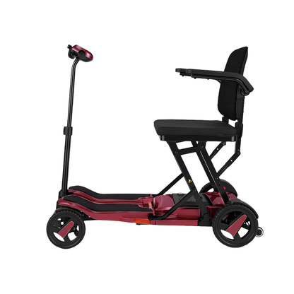 The ScootNgo Voyager Lightweight Folding Scooter is a compact, three-wheeled mobility scooter with a maroon and black frame, black seat with armrests, handlebars, and is shown from the side against a white background.