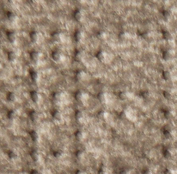 Close-up of a textured beige carpet with a grid pattern and soft, raised fibers—an inviting addition to relax beside your Golden Tech PR527 Cloud Recliner With Lift Assist & Twilight - SM/MD. The carpet’s neutral tone creates a cozy, clean atmosphere.