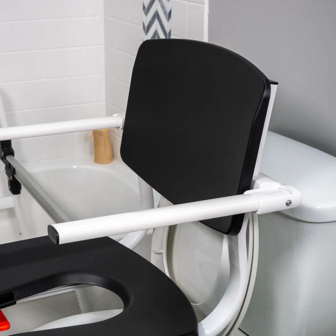 Close-up of Accessories and Parts for ShowerGlyde® Transfer Benches, including a padded seat cover for enhanced comfort, shown on a black and white toilet safety frame in a tiled bathroom with a nearby bathtub.