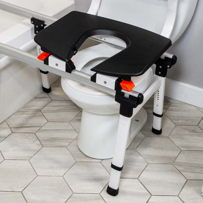 The ShowerGlyde SG2 Sliding Transfer Bench for Tub & Toilet Transfers is placed over a standard toilet, aiding individuals with mobility needs. The bathroom floor showcases light-colored hexagonal tiles.