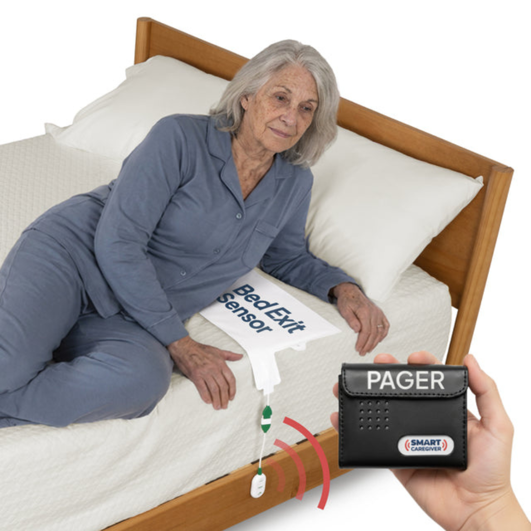 An elderly woman in pajamas is lying on a bed next to a Bed Exit Sensor pad, while a hand holds the SmartCaregiver Pager from the SmartCaregiver Pager Bed/Chair Exit Alert & Systems, with red signal lines depicting wireless connectivity as part of the alert system.