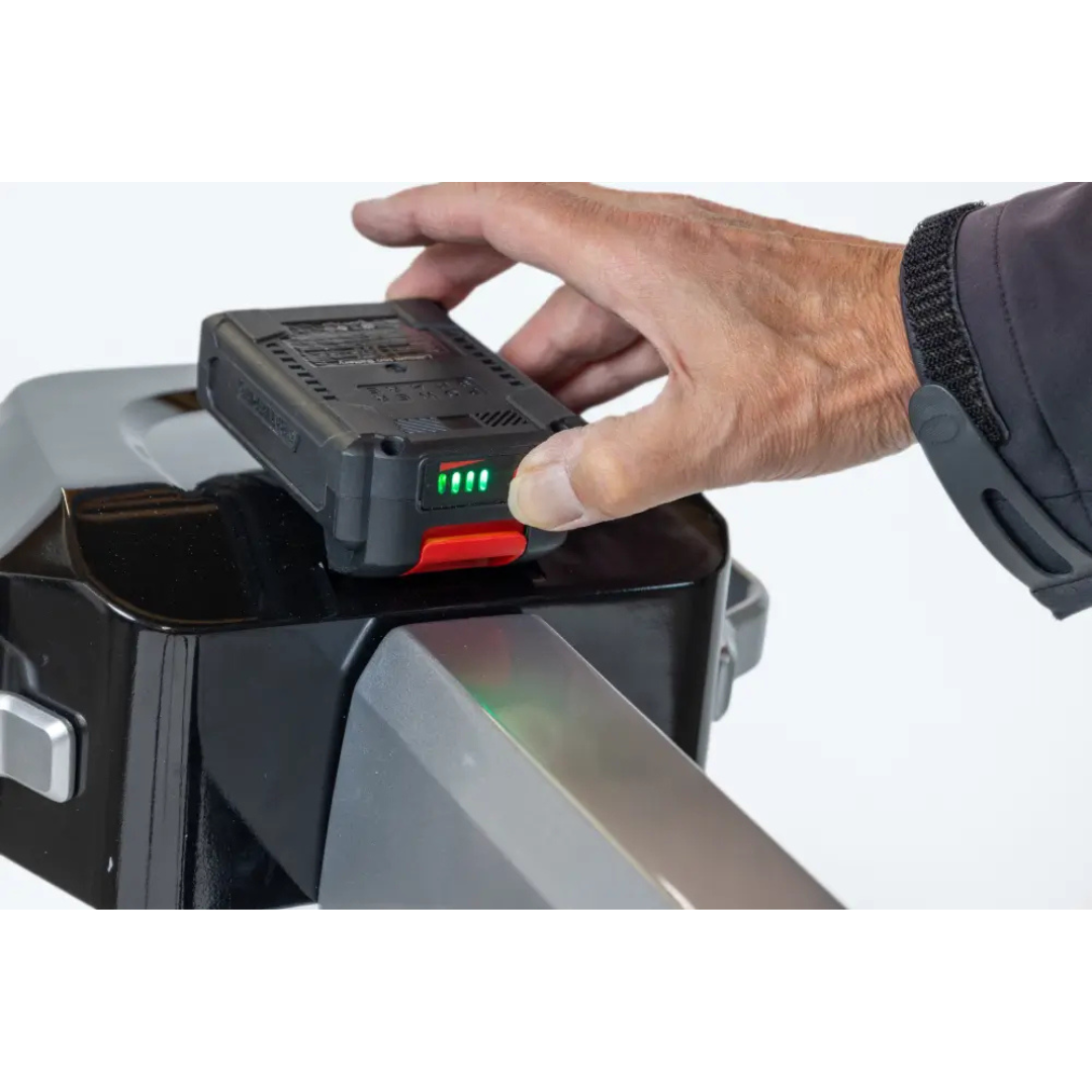 A hand places the Spare Battery For Atlas 4 Car Lift, featuring green indicator lights, onto a black and silver device—likely the Atlas 4 Car Lift—for charging or to connect a replacement battery.