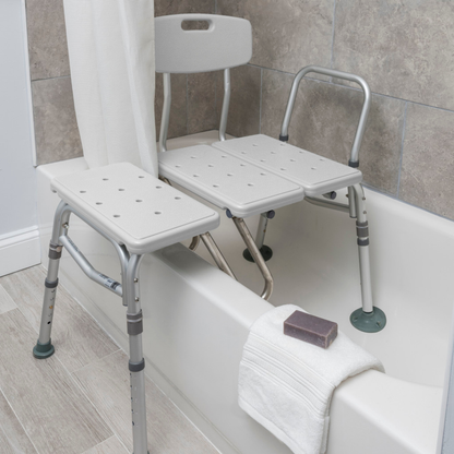 The Drive Splash Defense™ Transfer Bench with Curtain Guard Protection is a white adjustable shower bench with backrest for seniors, spanning the bathtub for safer bathing. A white towel and bar of soap rest on the tub edge.