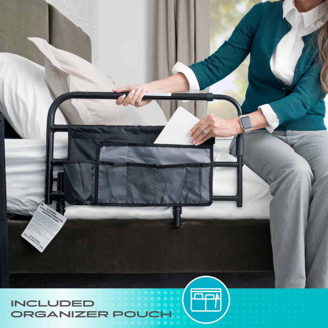 A person on a bed slides paper into a black organizer pouch attached to the Stander Wonder Extendable Pivot Bed Rail. The phrase "Included Organizer Pouch" is displayed at the bottom of the image.