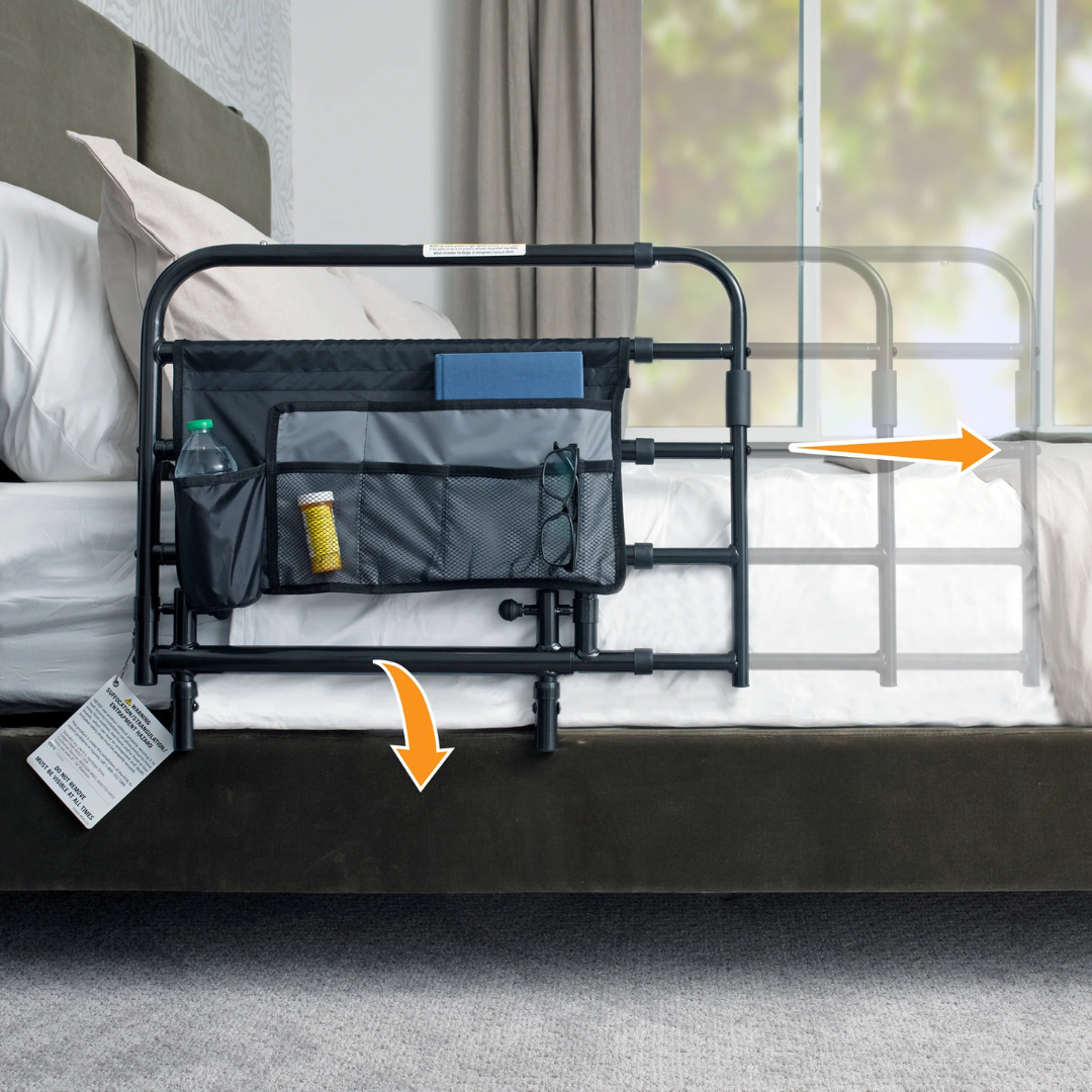 The Stander Wonder Pivot Bed Safety Rail - Tall is a black adjustable rail with storage pockets for a water bottle, pill bottle, book, and glasses—ideal for nighttime safety and convenience. Orange arrows indicate its adjustability.