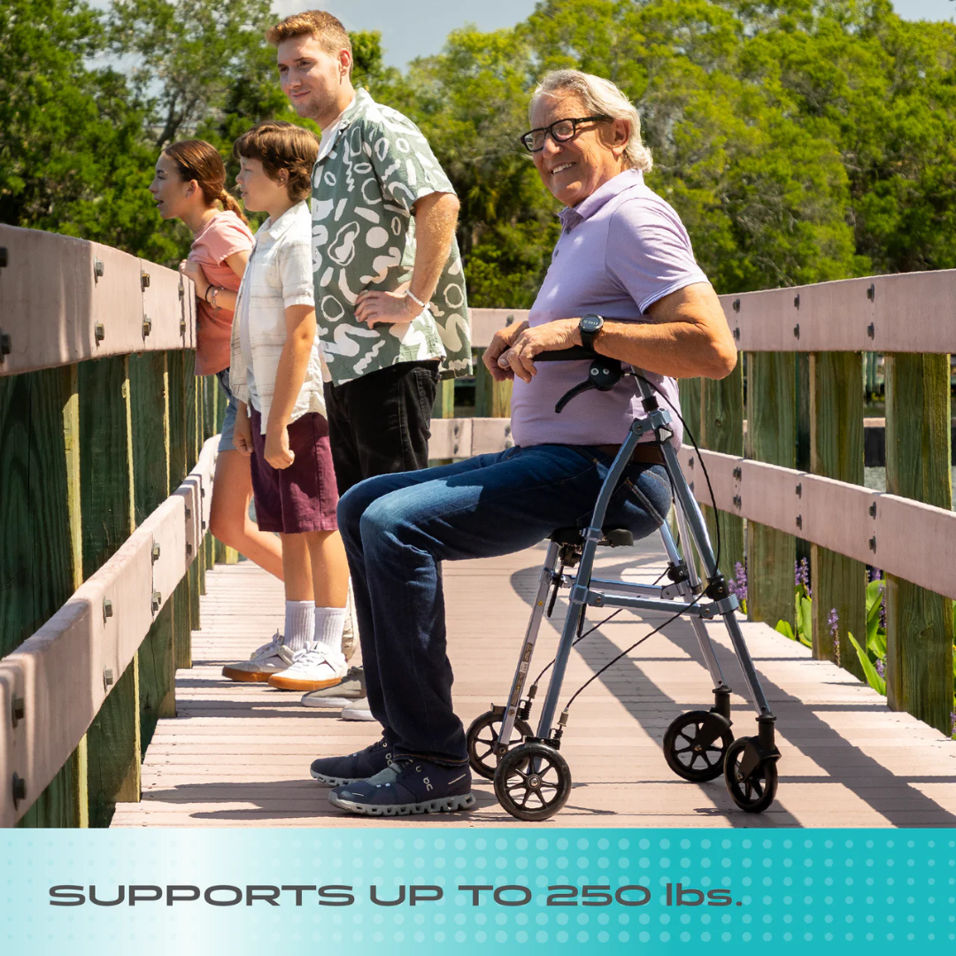 An older man smiles at the camera while seated on a Stander Wonder Rollator Plus on a wooden boardwalk. Three others stand nearby, enjoying the view. Text reads: SUPPORTS UP TO 250 lbs.