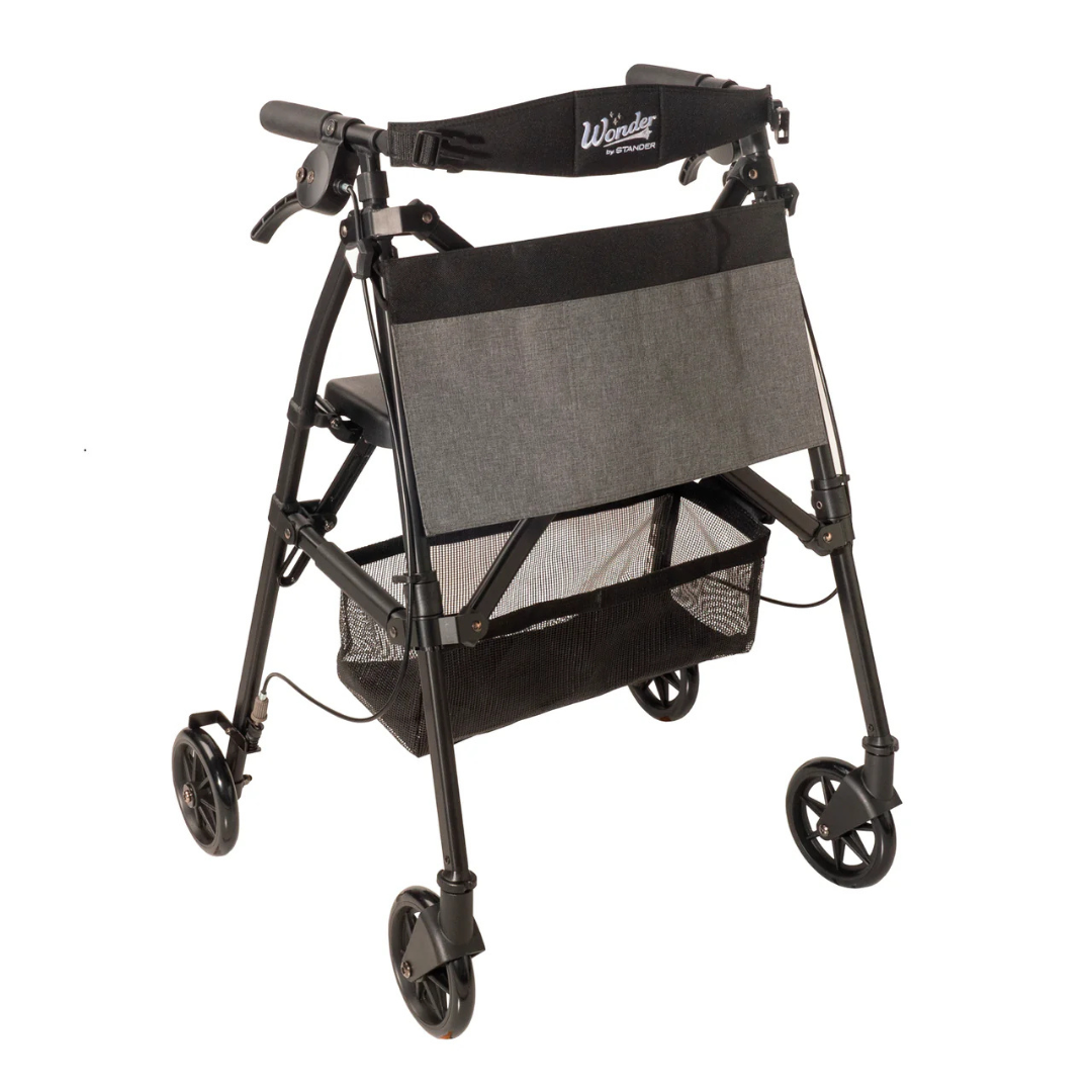 The Stander Wonder Rollator Plus is a black and gray compact folding rollator featuring a seat, backrest, storage pouch, and handle brakes to assist with mobility.