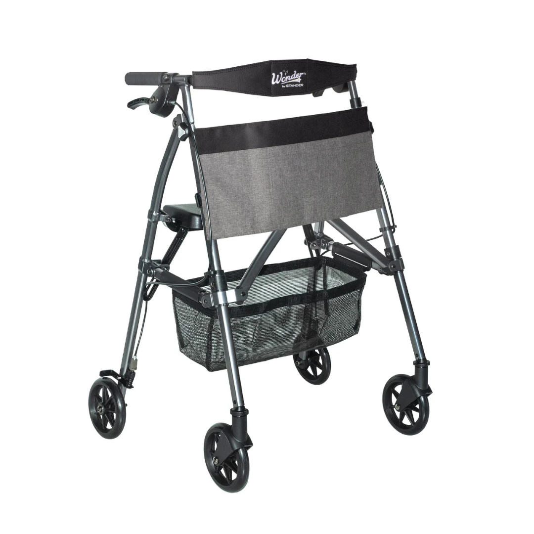 The Stander Wonder Rollator Plus is a lightweight, compact folding rollator with four wheels, a padded seat and backrest, hand brakes, large front storage pouch, mesh basket, and metallic gray frame—perfect for travel.