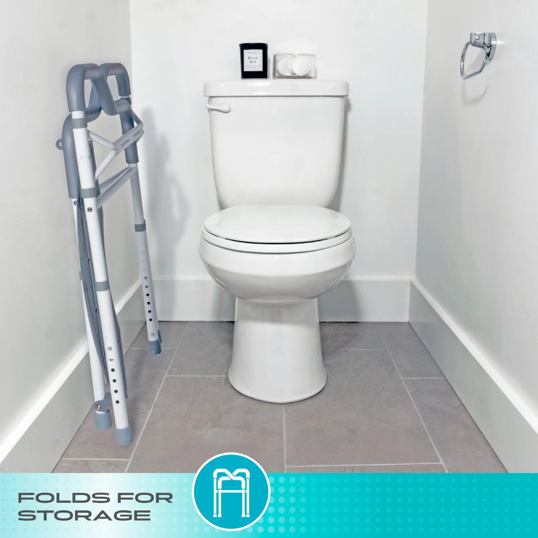 A Stander Wonder Toilet Safety Rails & Standing Aid, folded and placed beside a white toilet in a clean bathroom with light grey tile flooring. Text on the image reads: Folds for storage—ideal for bathroom stability and support.