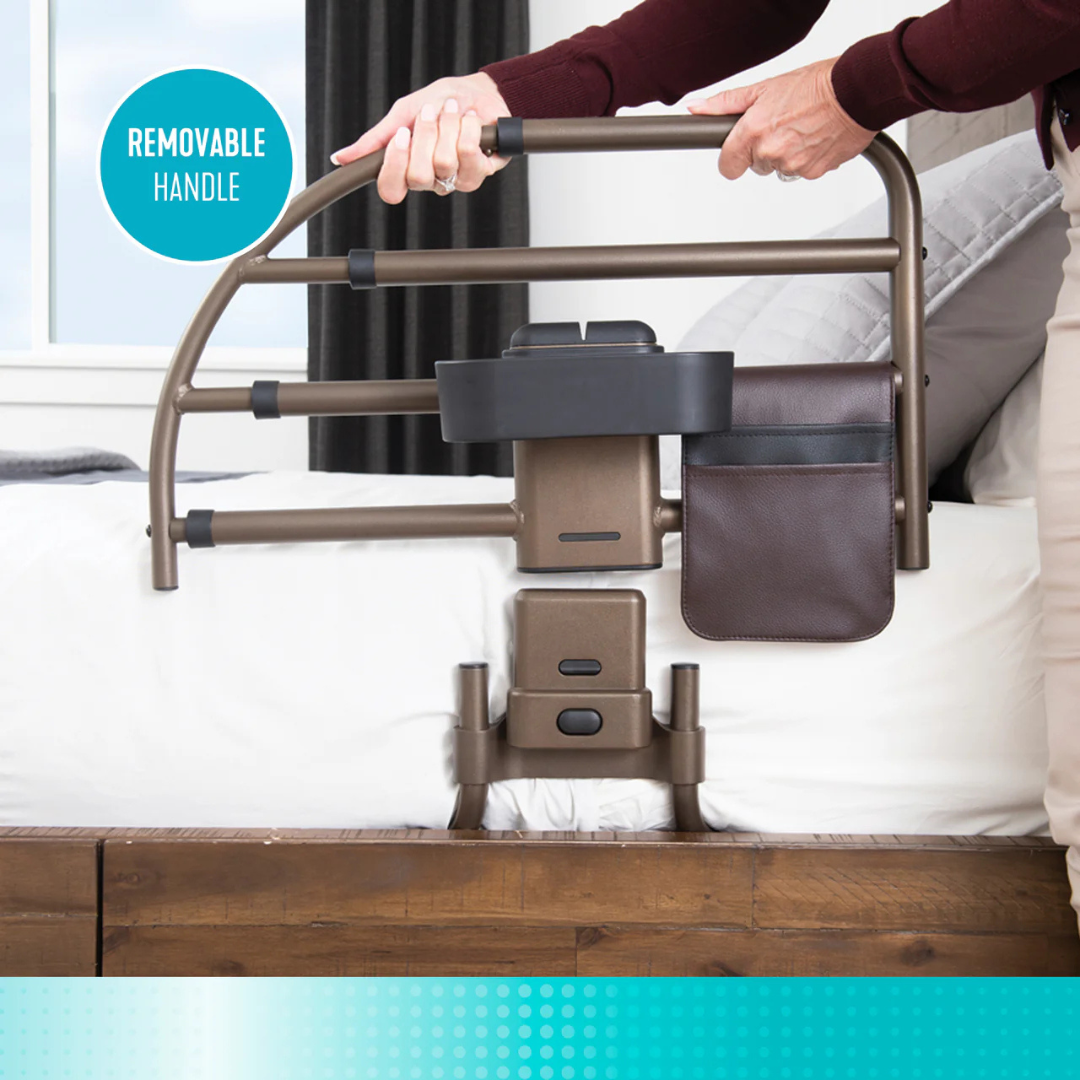 A person adjusts the Signature Life Freedom Click Extendable Bed Rail, which attaches to the bed, has a removable grip, offers fall protection, features a storage pouch, and provides support for getting in and out of bed.