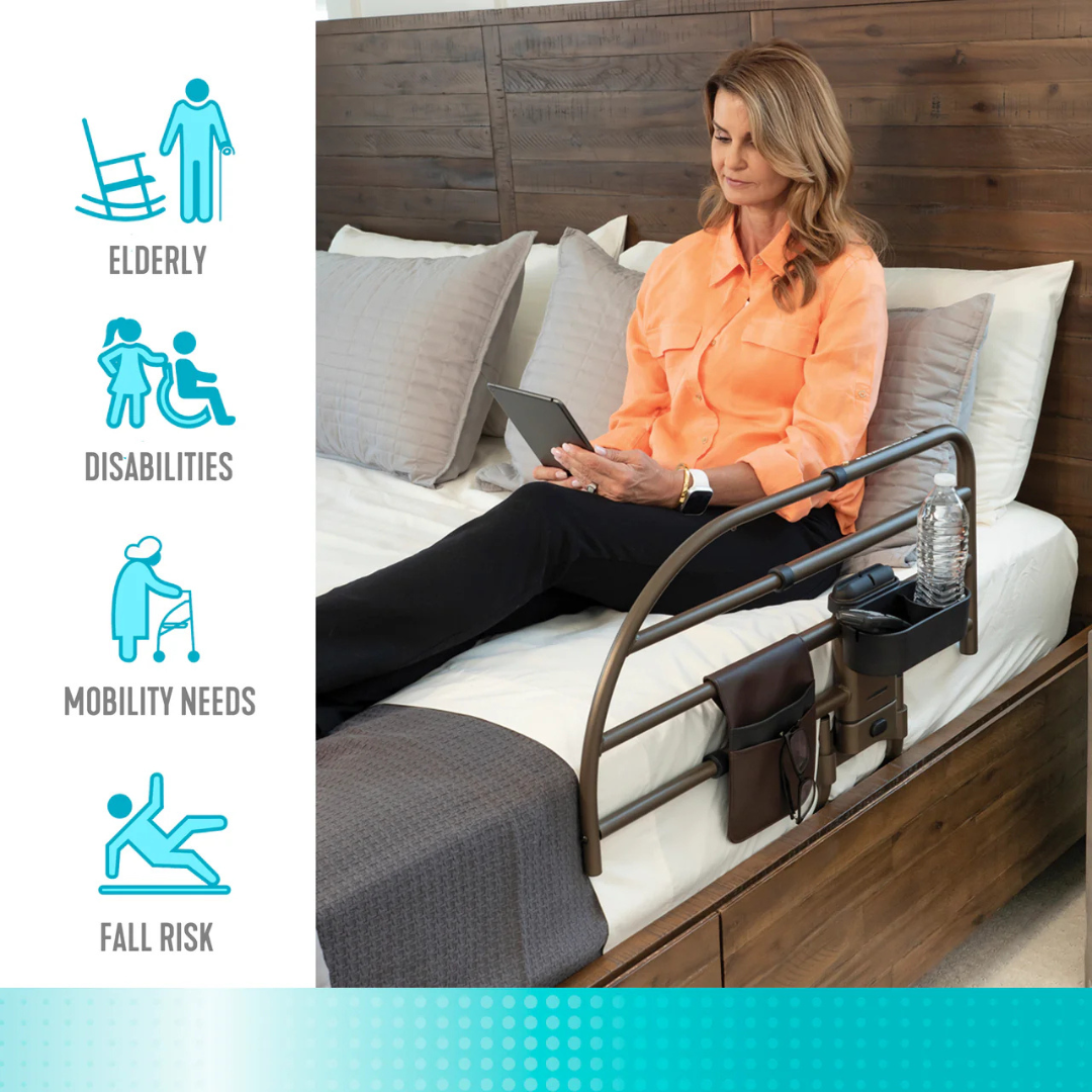 A woman uses a tablet on her bed with the Signature Life Freedom Click Extendable Bed Rail, featuring an adjustable handle, pouch, and cup holder. Icons show it offers fall protection for seniors and those with mobility challenges.