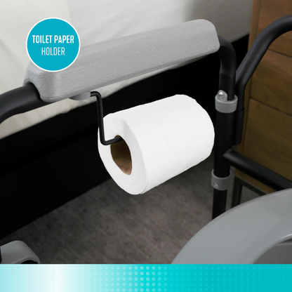 A close-up of a white toilet paper roll on the holder attached to the armrest of the gray Stander Universal Bedside Commode with TP Holder, featuring a blue "Toilet Paper Holder" label in the top left corner.