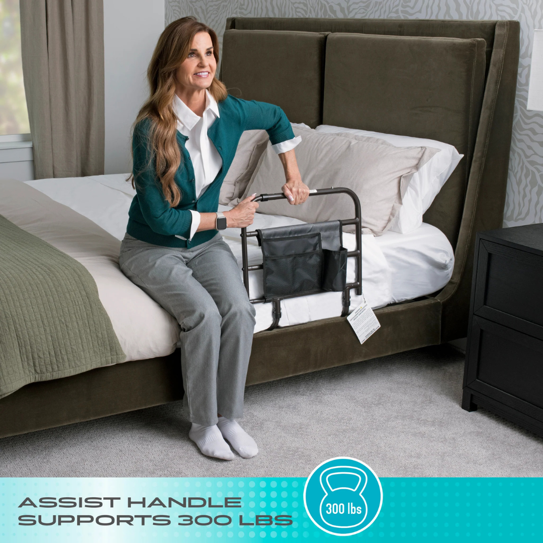 A woman sits on a bed using the Stander Wonder EZ Adjust Bed Rail - Extendable, a black assist handle attached to the bed frame; text overlay reads ASSIST HANDLE SUPPORTS 300 LBS alongside a weight icon showing 300 lbs.